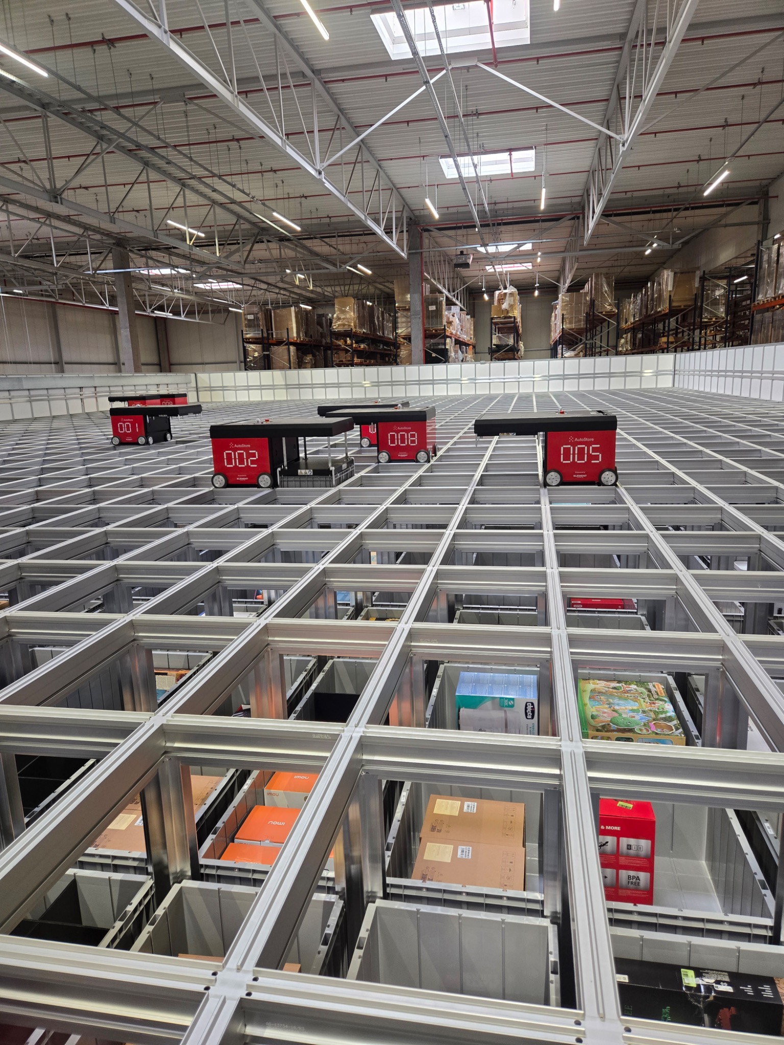 Roboty AutoStore pracujące nad siatką pojemników w magazynie XBS Logistics